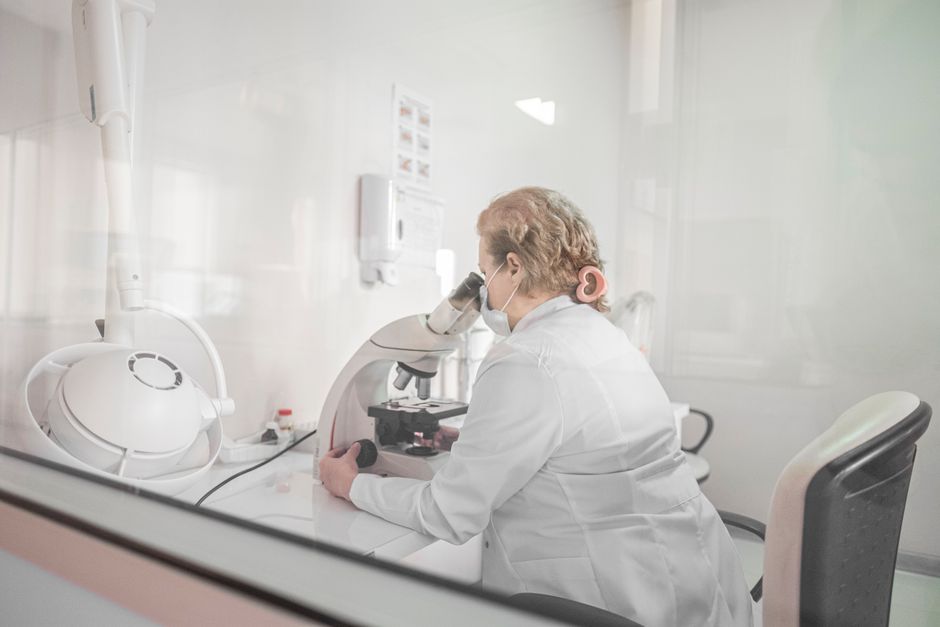 A scientist works with a microscope in a bright, modern lab setting, wearing a lab coat.
