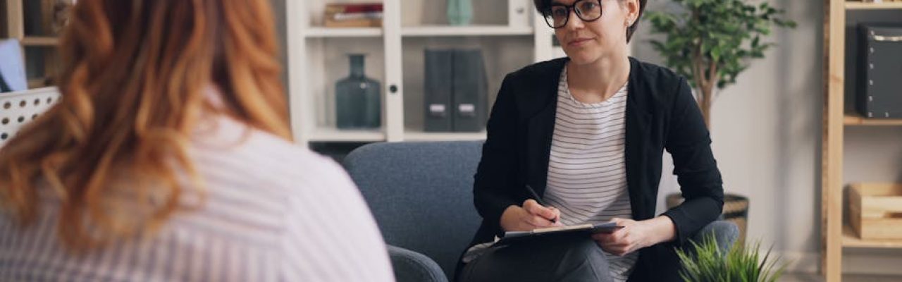 A therapist and patient having a counseling session in a modern office sitting area.