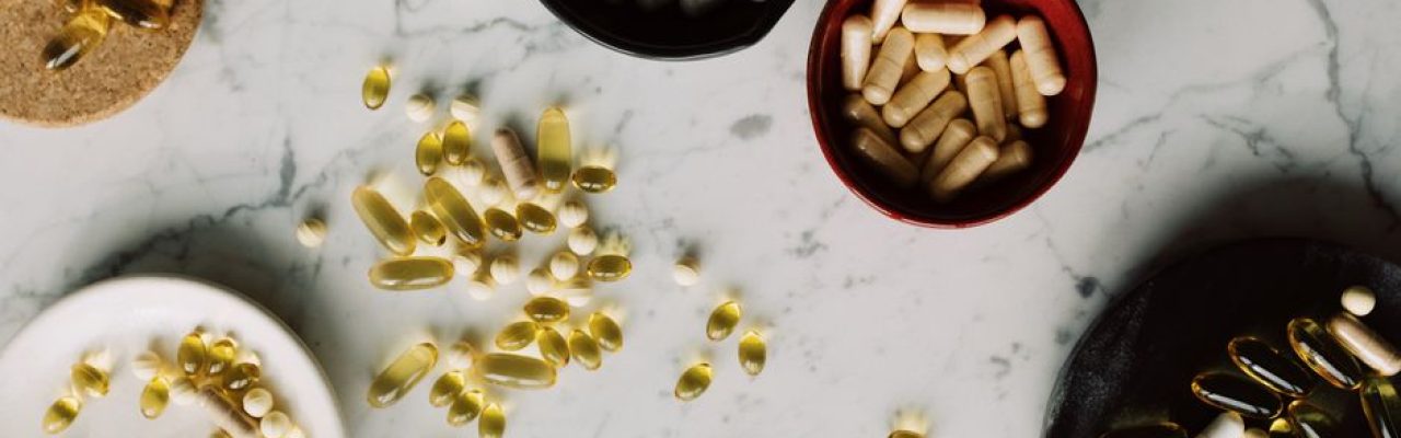 Assorted capsules and pills on a marble surface, illustrating healthcare and medication themes.