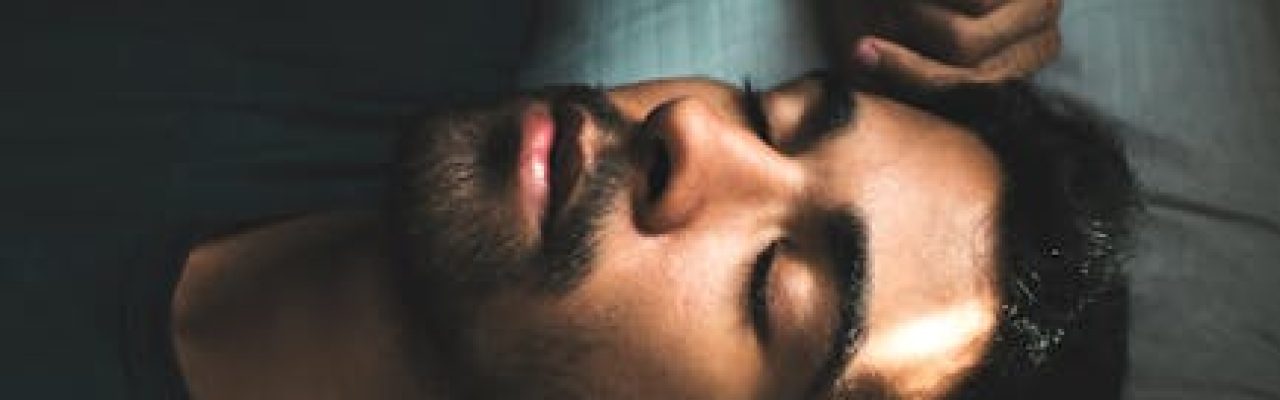 A serene portrait of a young man sleeping peacefully in a sunlit bedroom setting.