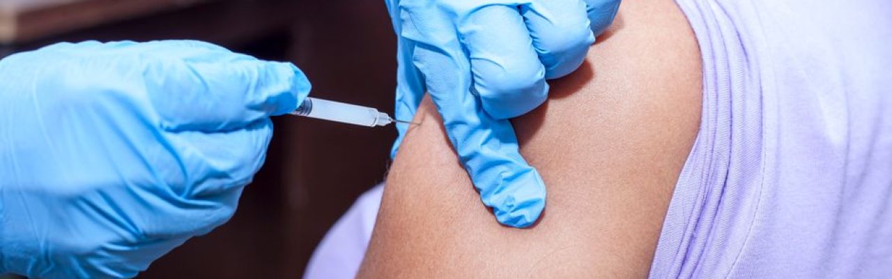 Close-up shot of a healthcare professional giving a vaccine injection.