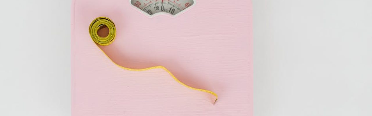 Top view of floor scales for weight control and measuring tape for controlling body shapes on white background