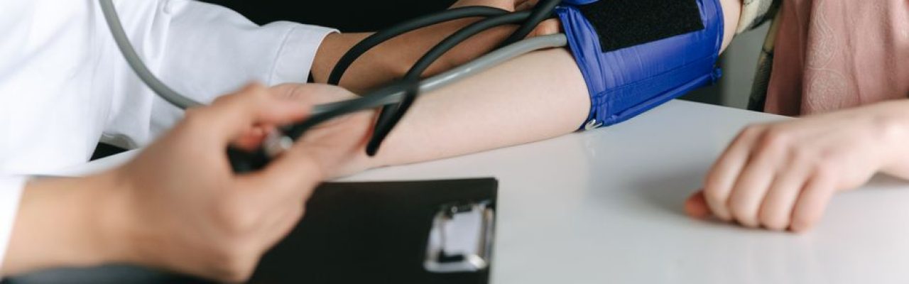 A healthcare worker uses a sphygmomanometer to check a patient's blood pressure in a medical office.