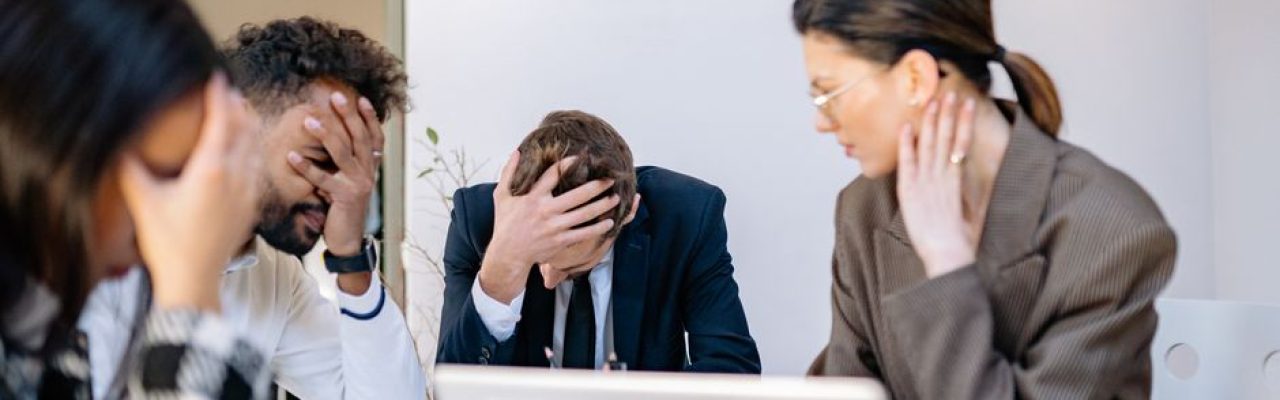 A group of stressed business professionals in an office setting, overwhelmed by work.