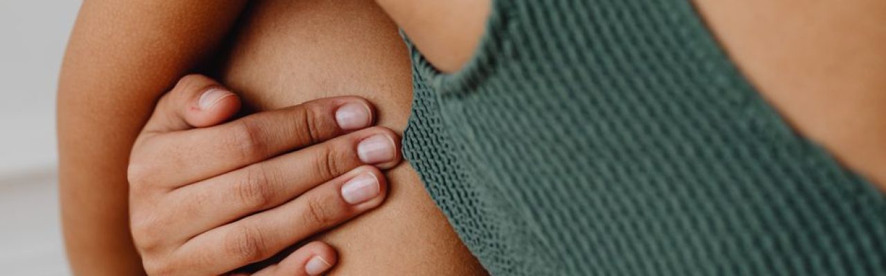 A close-up of a person's hand gently resting on their knee in a minimalist, intimate setting.